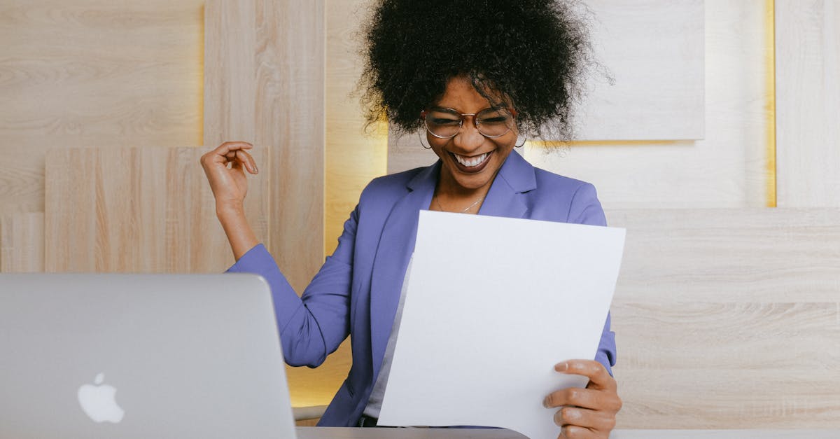 What We Do A cheerful woman celebrates her success at work, looking at a document in an office setting.