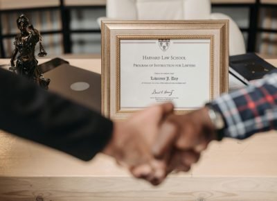 pexels photo 8112119 8112119 Harvard Law School degree with handshake representing achievement and professional agreement.